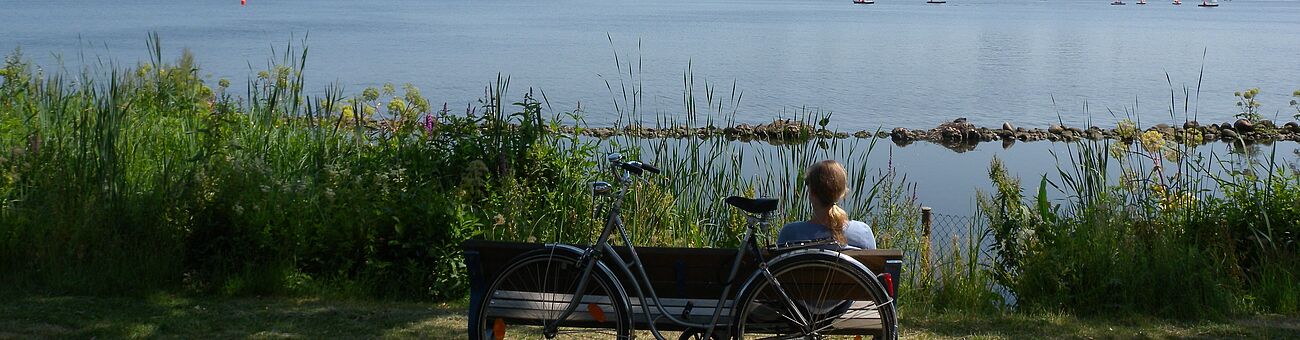 woman with bike on bench by the river