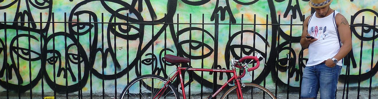 man standing next to bike before graffiti wall